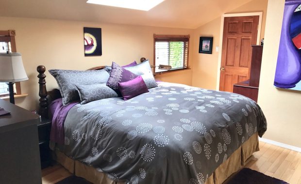 Second master bedroom with large bed and bright art and bedding for comfort when travelling