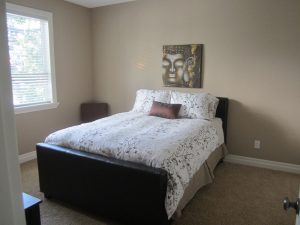 Spasre bedroom with neutral walls and bright bedding and art on wall