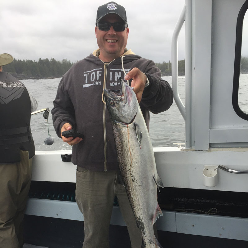 Man holding large fish while standing on boat Vancouver Island, BC