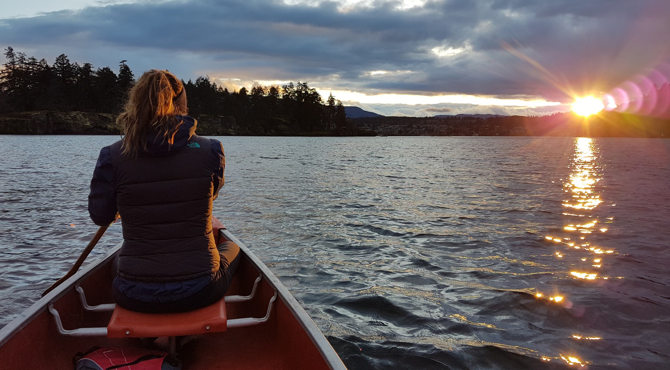 Woman in canoe on the ocean with sunset