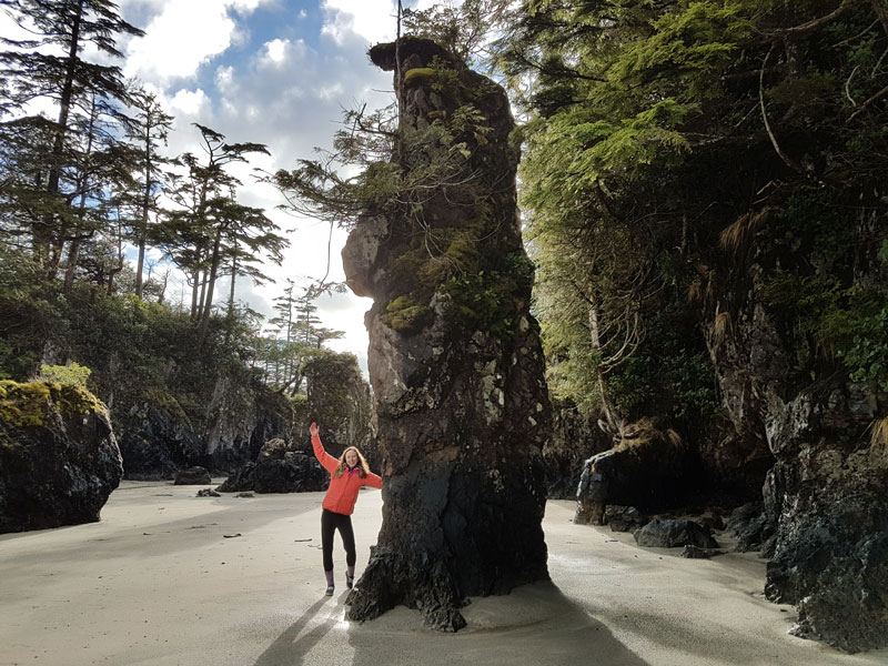 Woman posing beside large rock formation on Vancouver Island, British Columbia Canada