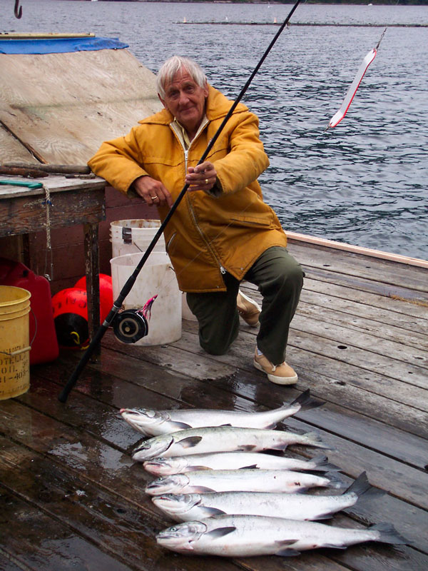 Senior citizen kneeling on dock with 6 fish that he caught